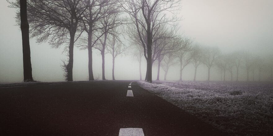 A dark road with fog and snow. 