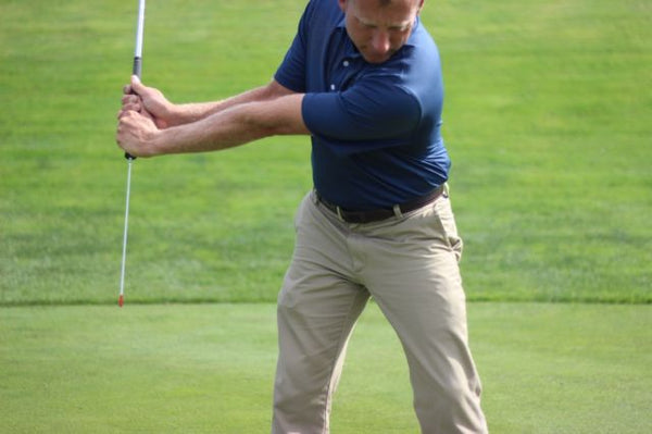 Image of a male golfer using the lag stick, a popular golf training aid