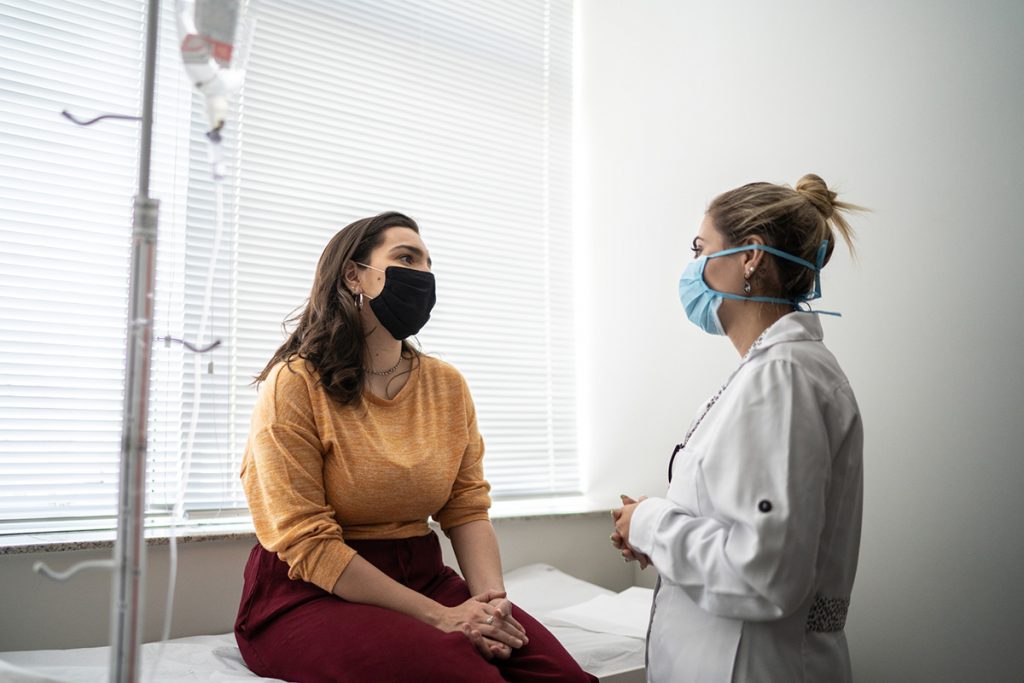 A woman talking to her doctor wearing protective face mask