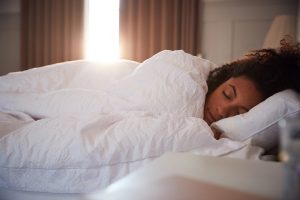 Peaceful Woman Asleep In Bed As Day Breaks Through Curtains