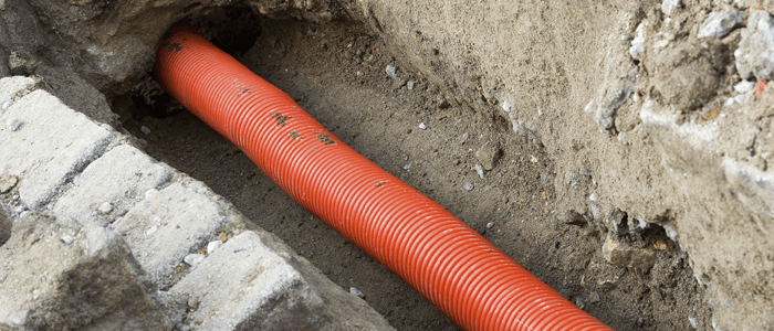 Orange underground pipe dug up from ground