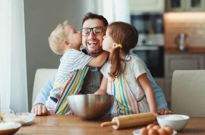 A boy and a girl kissing their father