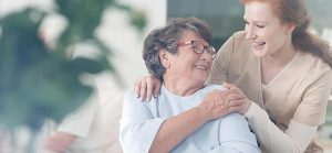 woman giving care to elderly woman for Quotacy blog The Best Term Life Insurance for Caregivers