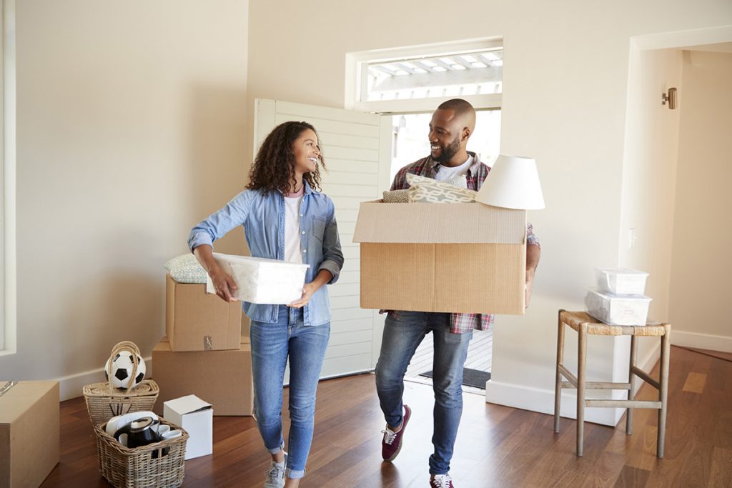 Couple Carrying Boxes Into New Home On Moving Day