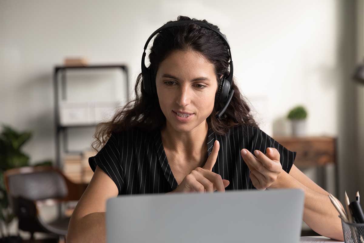 A heath coach conducts a call via laptop, wearing a headset