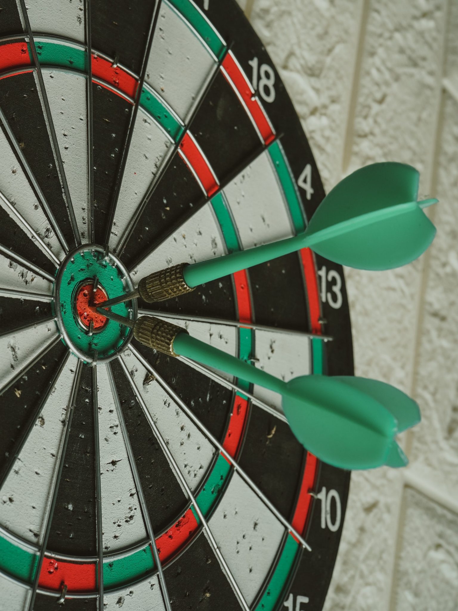 dartboard with green darts in bullseye