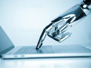 A metal robot hand is reaching out and pressing a key on a laptop.