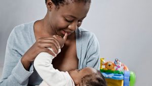 A photo of a young Black mother breastfeeding her baby daughter.