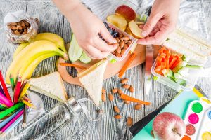 Mother preparing school lunch box of healthy snacks