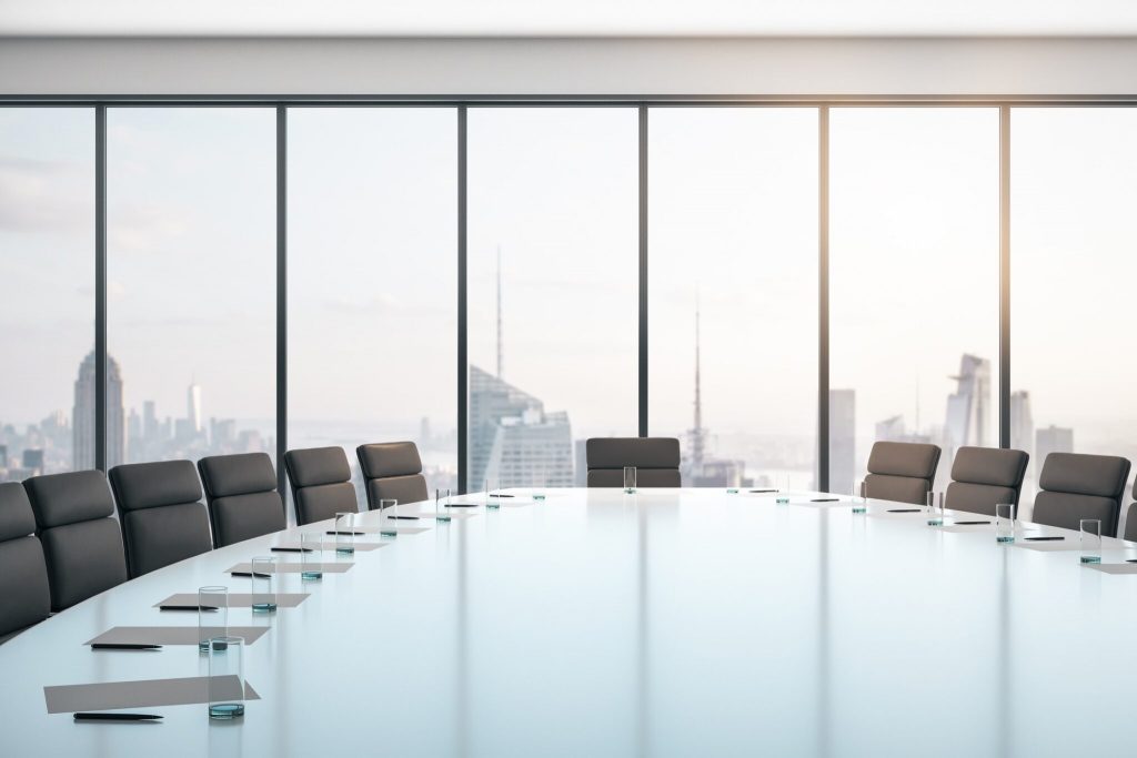 Conference room with table and chairs, large window and city view at sunrise, business concept.