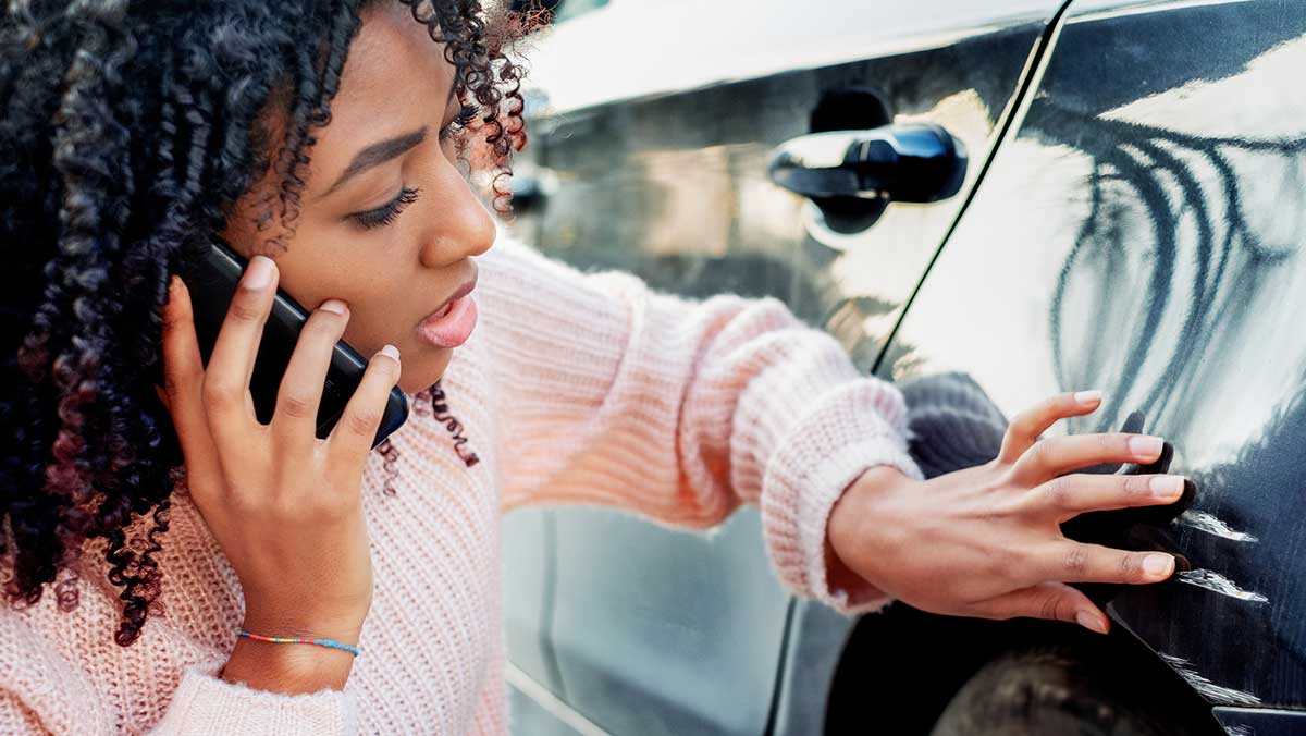 What to do when you get into a car accident - woman inspects damage to car