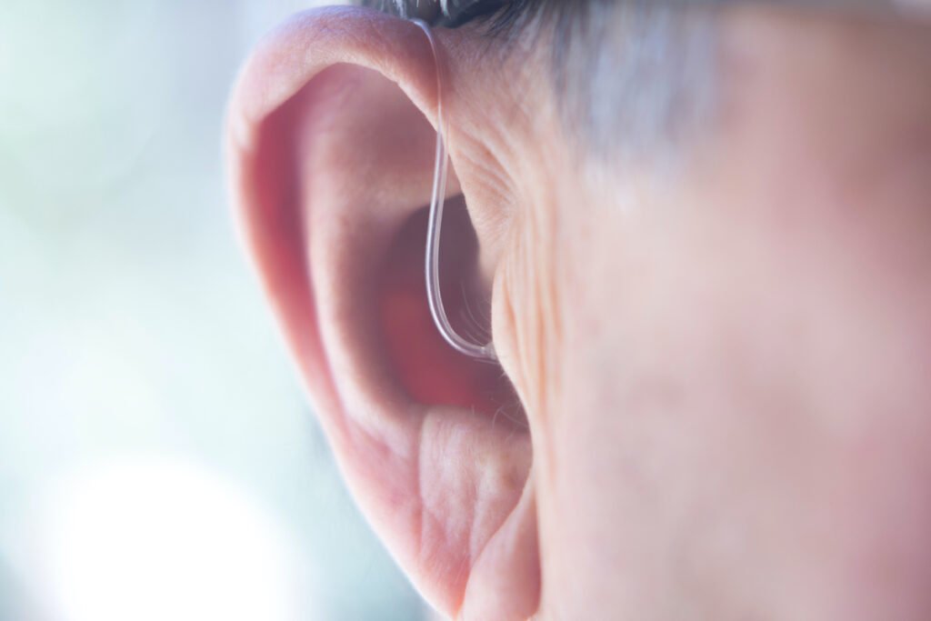 Modern digital in the ear hearing aid, in aged man's ear. 