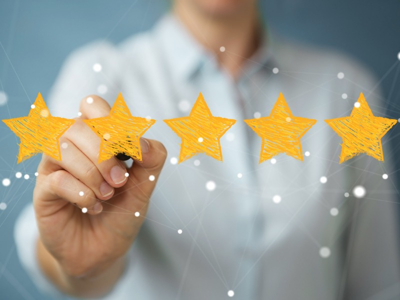 Blurred background of a businesswoman. She is reaching out with 5 hand-drawn stars to create a rating.