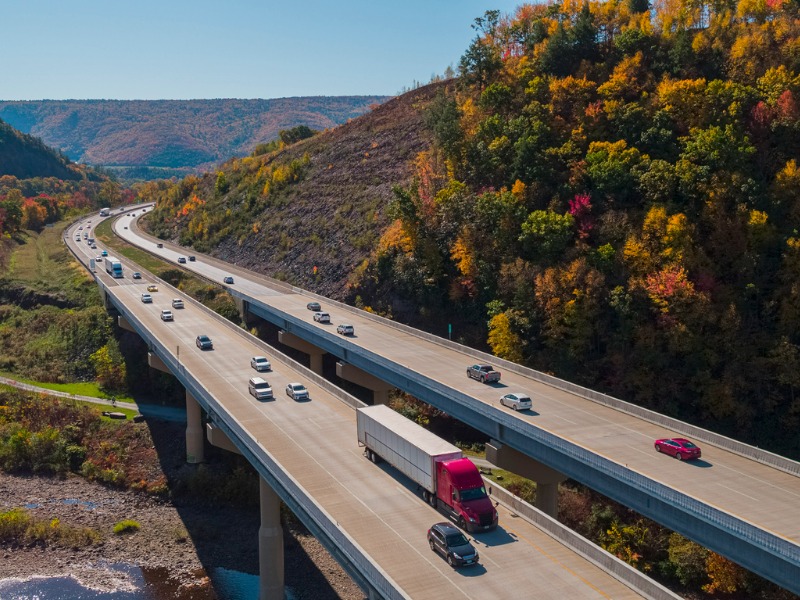 Private and commercial vehicles drive down a scenic highway. The high bridge at the Pennsylvania Turnpike on the sunny spring day. Lehigh Valley, Poconos region, Pennsylvania, USA.