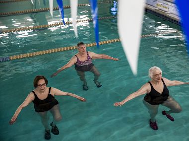 June Lieb, Nancy Weber and Miriam Cohen do single leg stands during swimming exercise class...