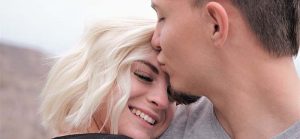 man in 20s kissing woman's forehead for Quotacy blog Is it a good idea to get life insurance in my 20s?