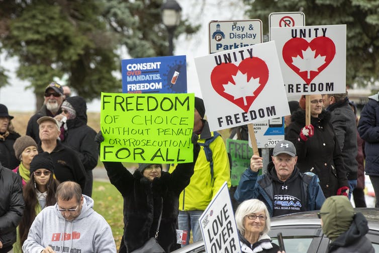 People at a vaccine mandate protest holding signs