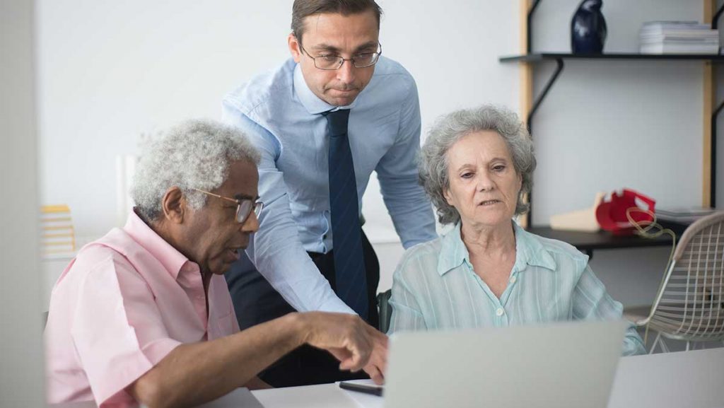 Older couple & business man looking at laptop - why do you need car insurance