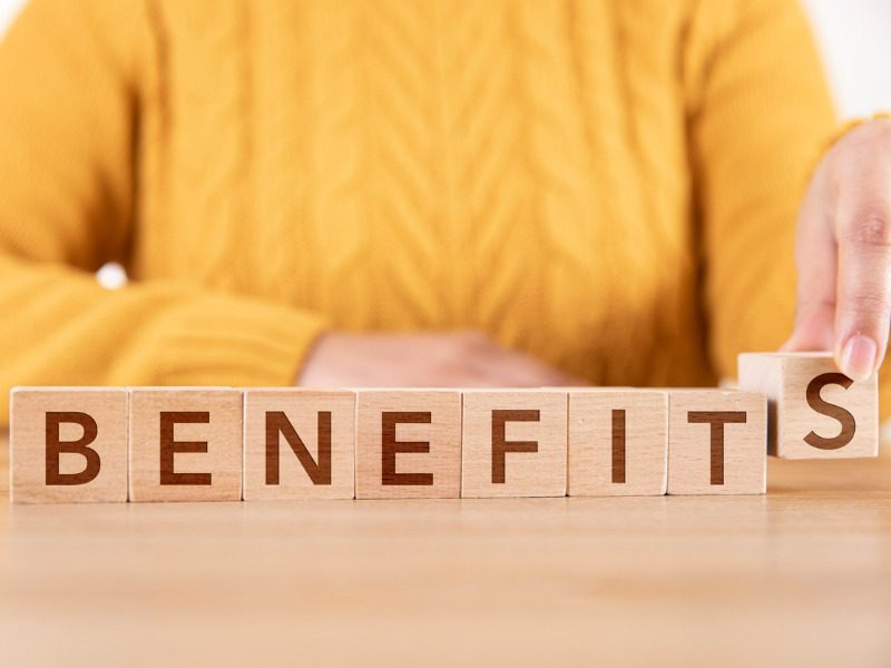 Woman is arranging wooden cubes and writing word benefits