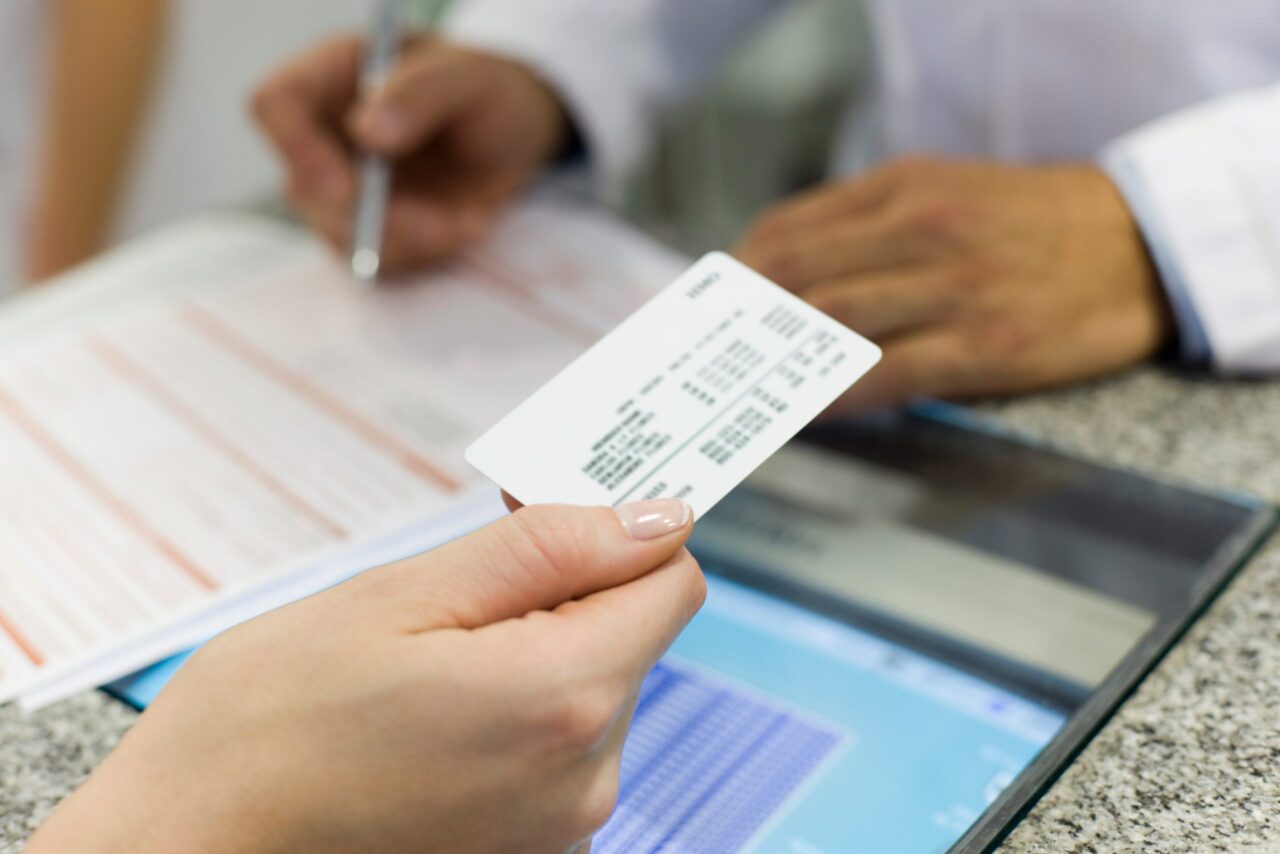 A patient hands over an insurance card to a doctor.