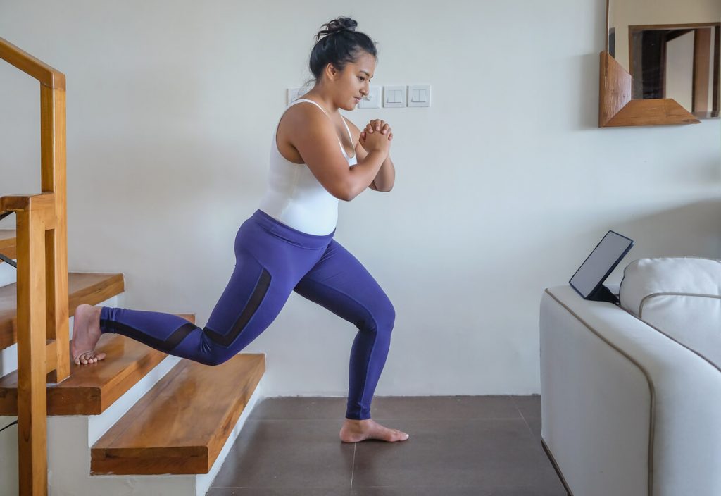 Woman performing a bulgarian split squat on the stairs in her home