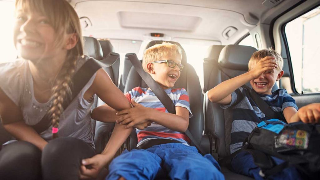 3 kids in back seat of car laughing - car activities for kids on road trips