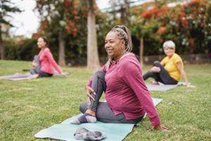 Three women on yoga mats outdoors stretching