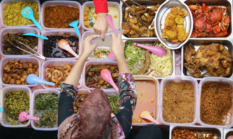 woman giving bag to customer at food stall