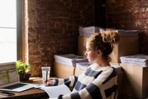 woman sitting at desk writing down goals