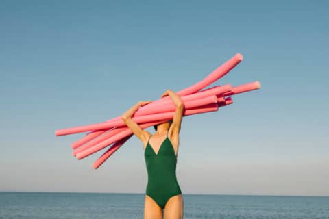 woman on the beach holding noodles