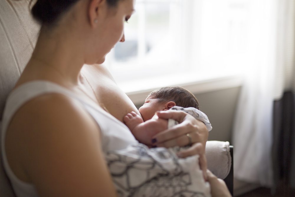 Woman breastfeeding her infant son by a window