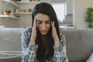 A young woman massages her temples in the midst of a migraine