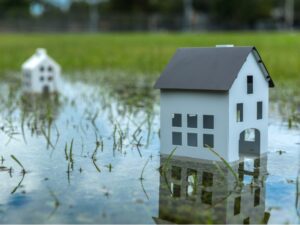 two miniature white houses resting in a puddle outside