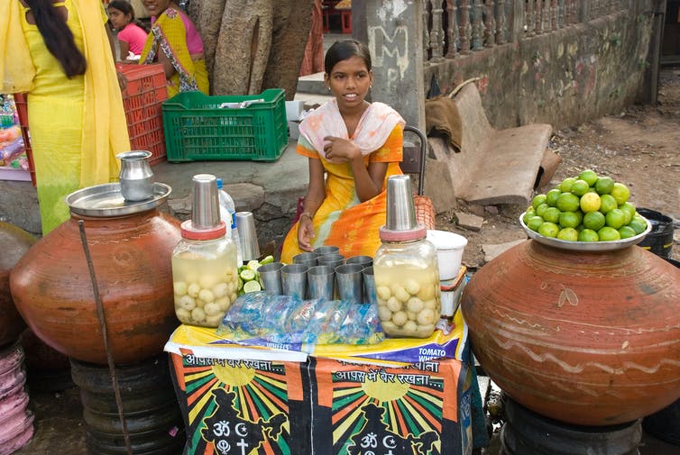 A woman at a stall selling drinks from jars.