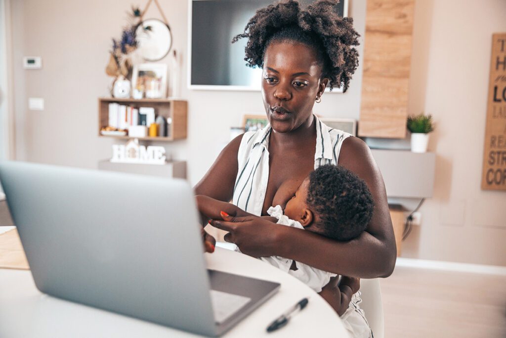 Business woman working at home while breastfeeding her baby