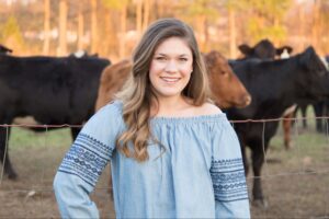 Logan smiling in front of several cows