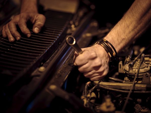 Mechanic holding a wrench with under car bonnet exposed