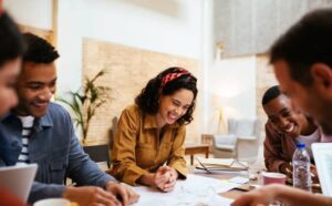 Happy multiracial casually dressed business people working together and sharing creative ideas about new project while having meeting in loft office