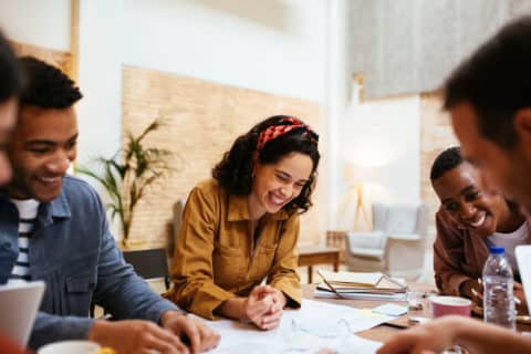 Happy multiracial casually dressed business people working together and sharing creative ideas about new project while having meeting in loft office