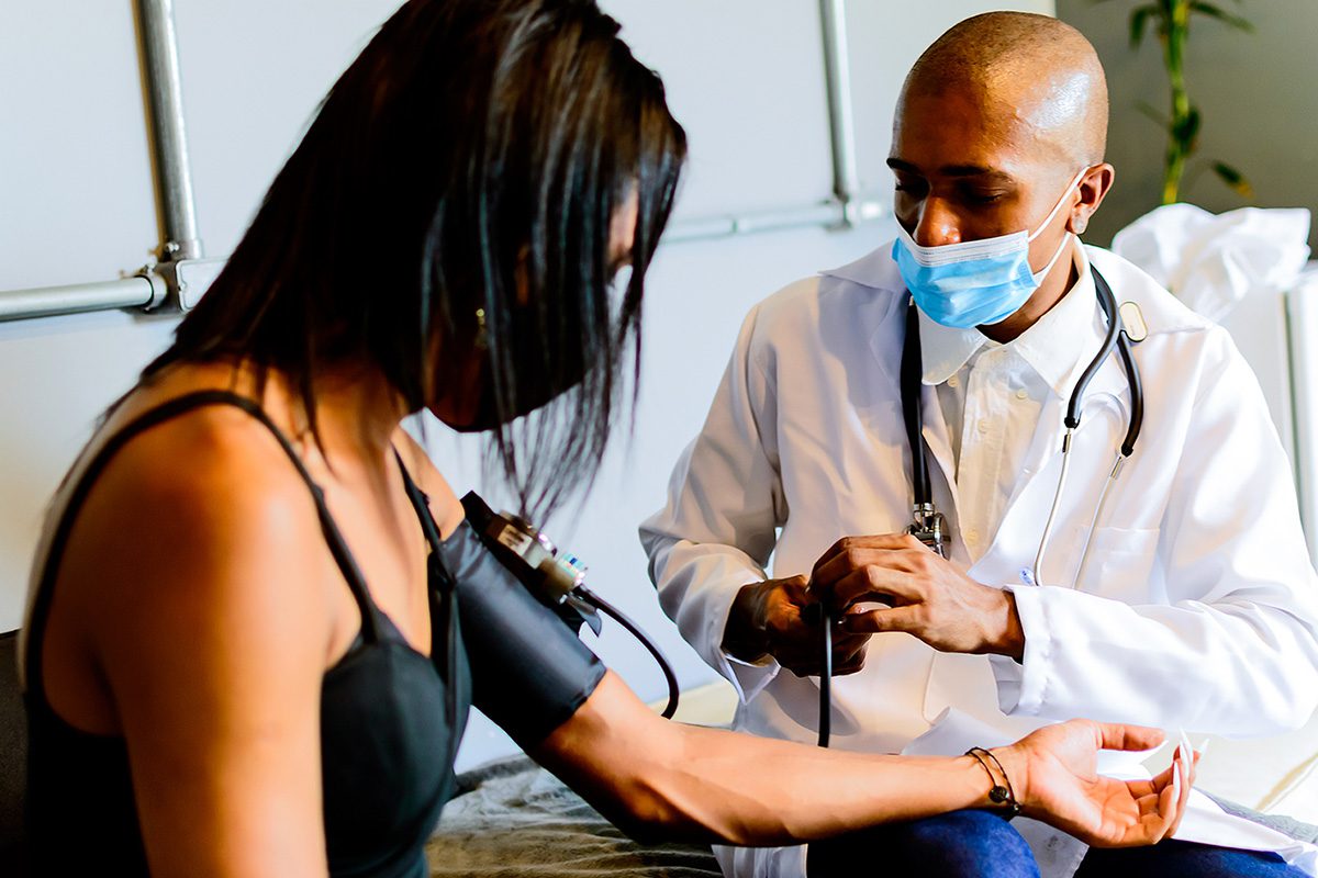 A doctor takes a non-binary woman's blood pressure