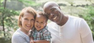 Image of couple holding their son smiling at the camera for Quotacy blog The Advantages of Life Insurance for Young Families.