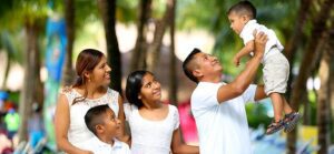 Image of father holding son up in air with family looking on for Quotacy blog When Should Someone Else Own My Life Insurance?