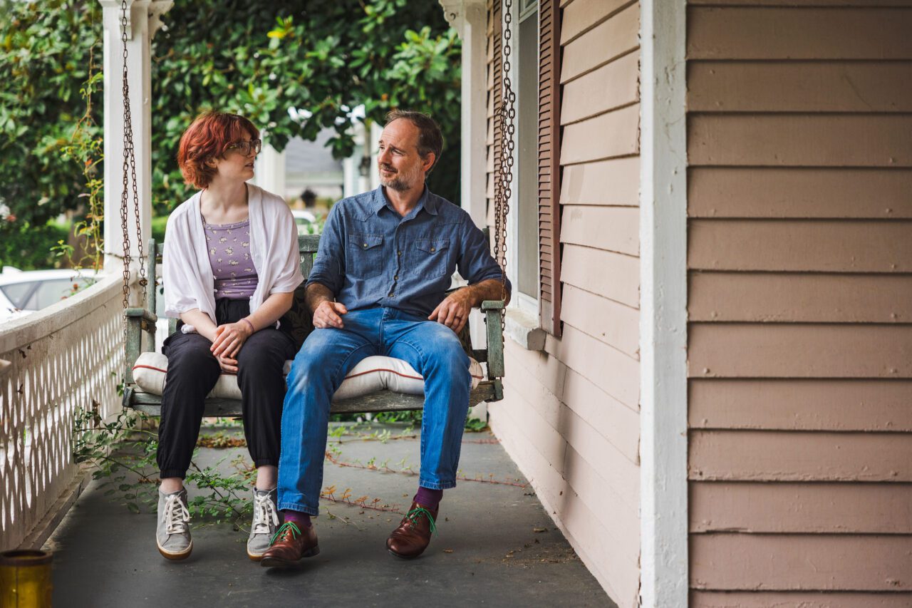 A photo shows Frankie and Russell Cook sitting on a porch swing together at home.