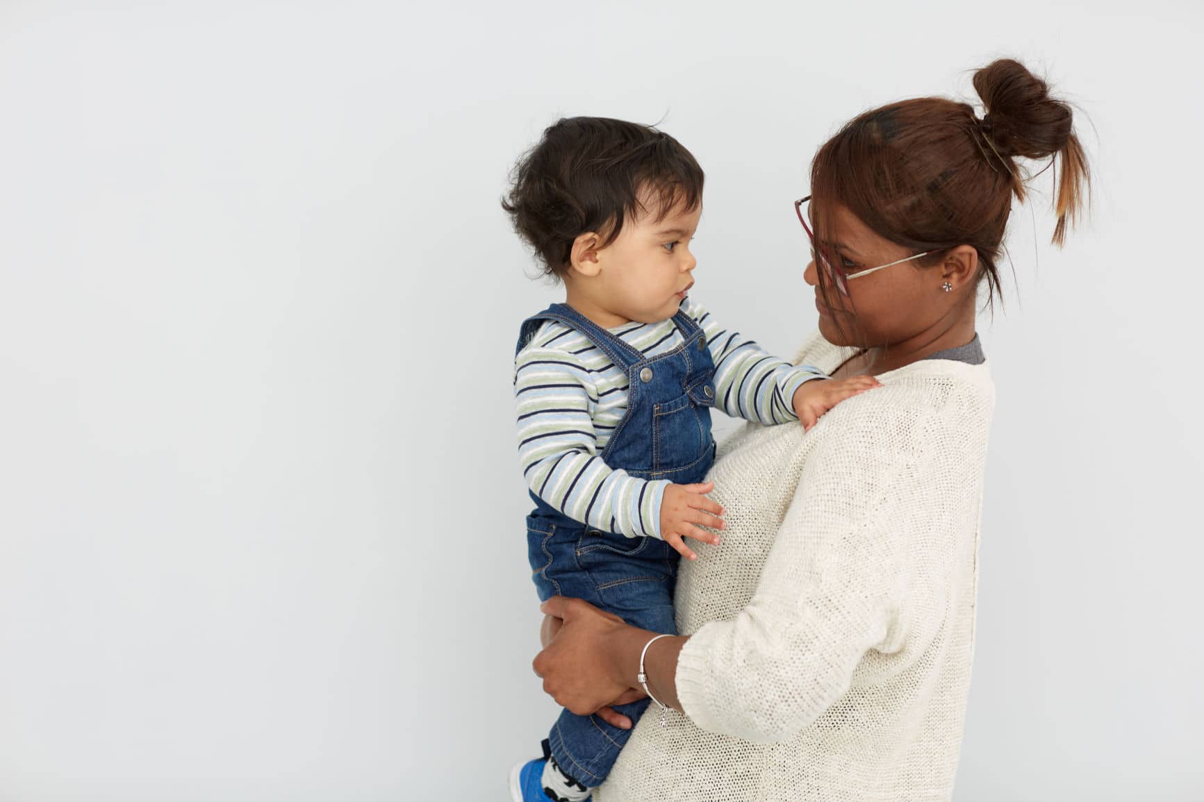 Mother holding toddler son near a blank wall