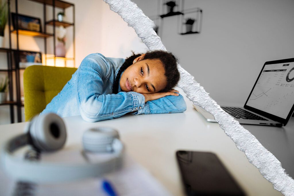 A depressed young womman lays her head on her desk