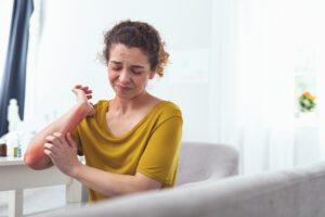 A woman scratches her arm.