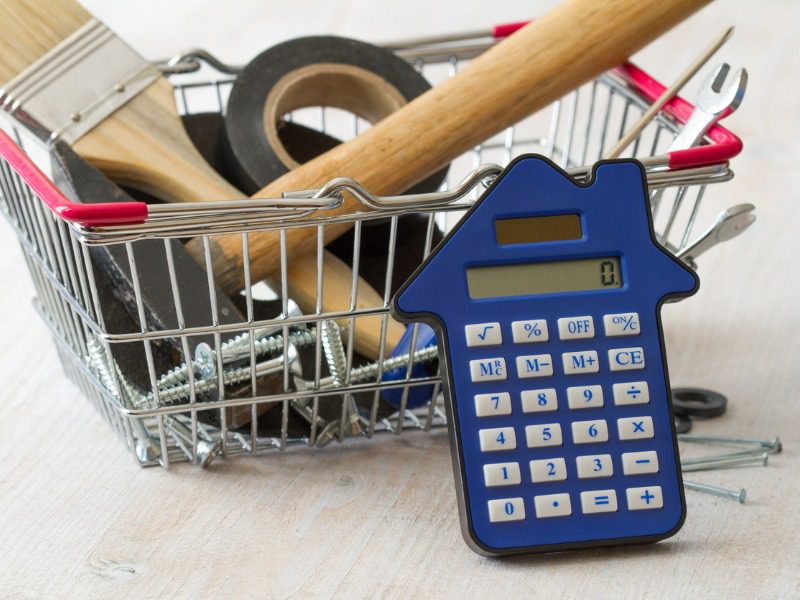 A house-shaped calculator resting on a basket of construction tools