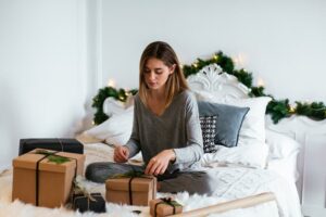 Woman sitting on the bed wrapping gifts