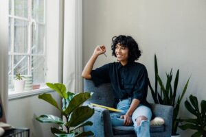 Woman sitting by the window smiling, working from home.