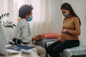 A young expecting mother talks with her physician